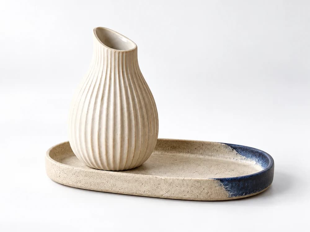 Lifestyle concept: ribbed ceramic vase and cobalt-accented tray with gentle grounding shadows on a white studio background